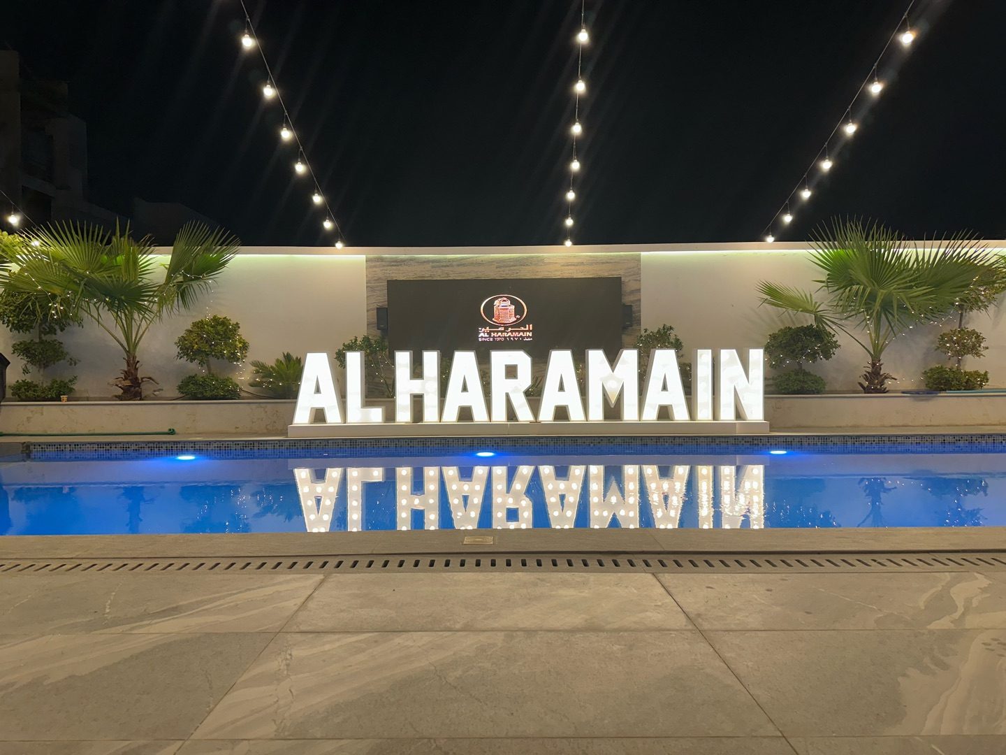 Al Haramain illuminated sign reflected in the pool at the OUD & PERFUME EVENT venue in Dubai